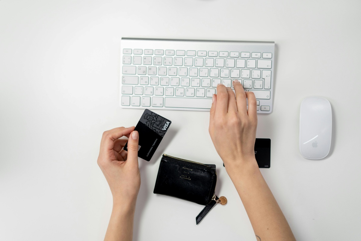 Person typing on keyboard and holding credit card