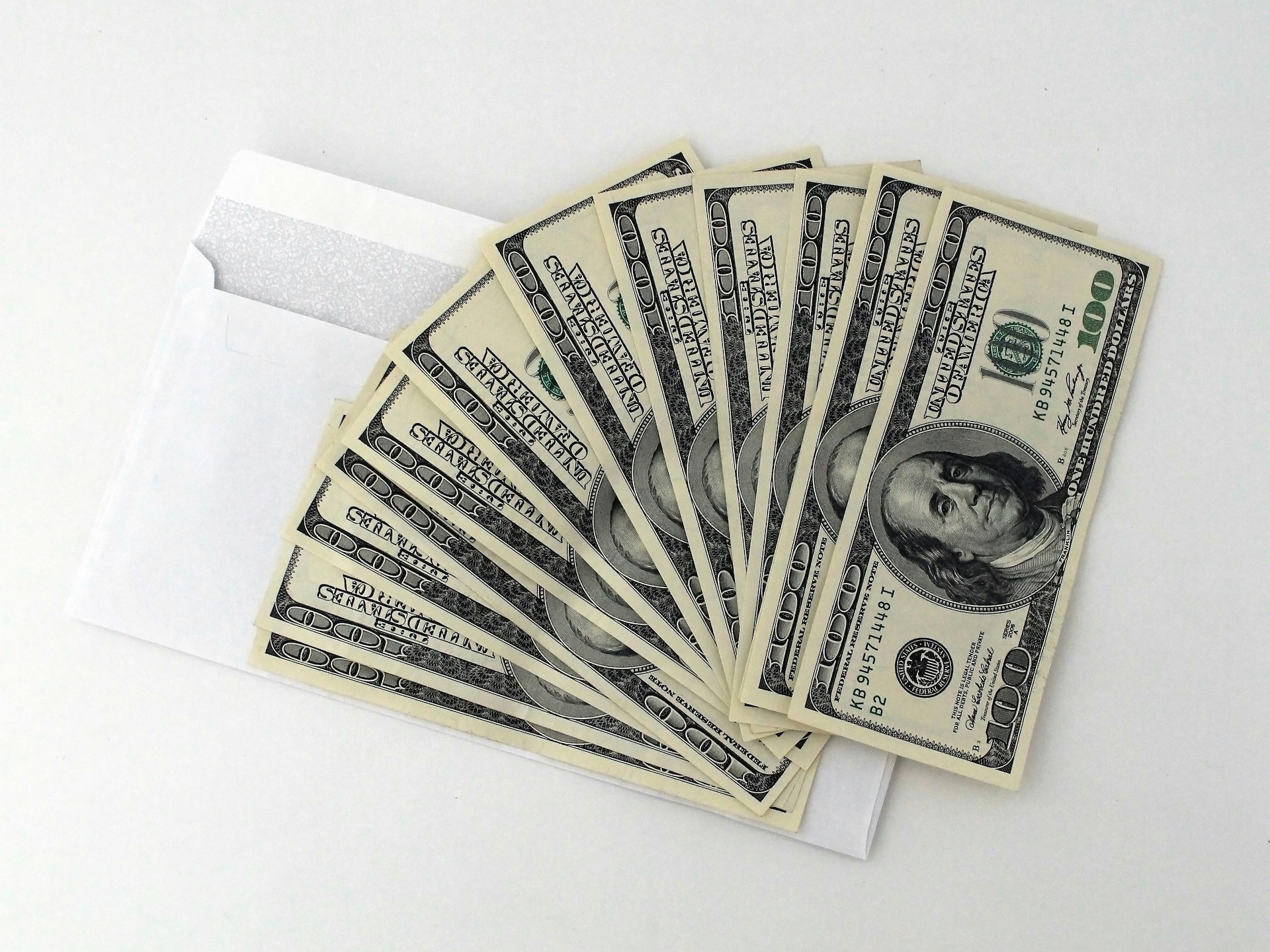 US dollars fanned out on top of envelope as part of business acquisition loan