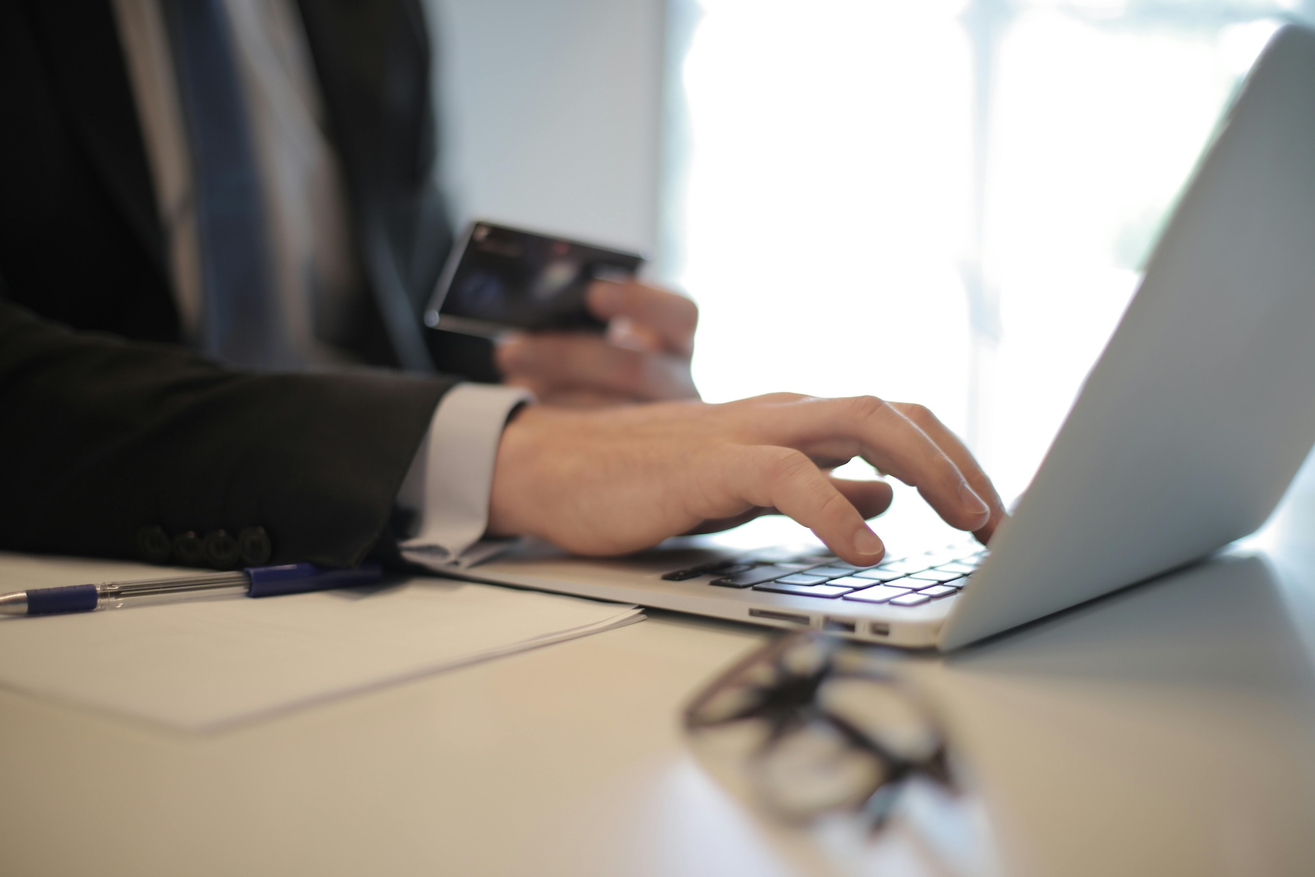 person in black suit typing on a computer