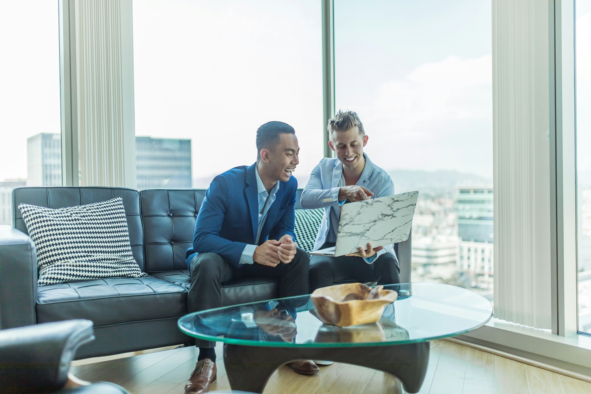 two men in suit sitting on sofa smiling a shopify capital